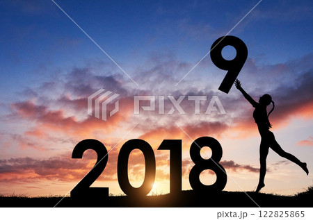 Silhouette of the girl who holds the numbers of the new year in the sunset. Concept of replacement 2018 to 2019 Silhouette of the girl who holds the numbers of the new year in the sunset. Concept of replacement 2018 to 2019 122825865