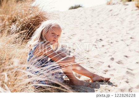 Cute little girl sitting on the sand 122826228