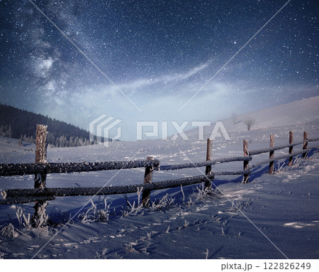 Winter landscape. Mountain village in the Ukrainian Carpathians. Vibrant night sky with stars and nebula and galaxy. Deep sky astrophoto 122826249