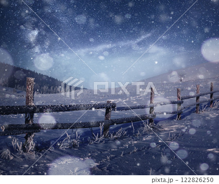 Winter landscape. Mountain village in the Ukrainian Carpathians. Vibrant night sky with stars and nebula and galaxy. Deep sky astrophoto 122826250