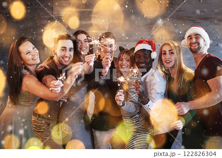 Party with friends. Group of cheerful young people carrying sparklers and champagne flutes. Bokeh light soft effect. 122826304