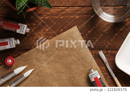 Preparing to draw. Tubes of acrylic paint, brushes, a glass of water on a dark wooden background. A place for your text. 122826378