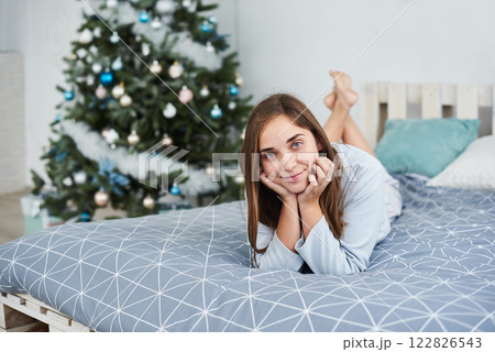 Beautiful girl lies on a bed in pajamas on Christmas morning 122826543