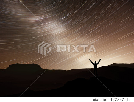 Silhouette of a happy photographer adventure trekking on mountain with real fantasy moving stars in the night sky. Conceptual of amazing nature with great dream journey and voyage scene 122827112