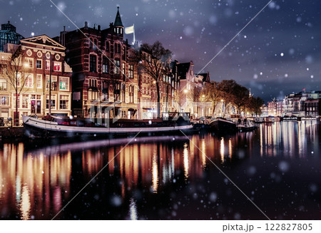Beautiful night in Amsterdam. Night illumination of buildings and boats near the water in the canal during a snowstorm. Bokeh light effect, soft filter 122827805