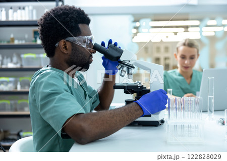 Man medical worker working in advanced scientific lab with microscope doing medicine research 122828029