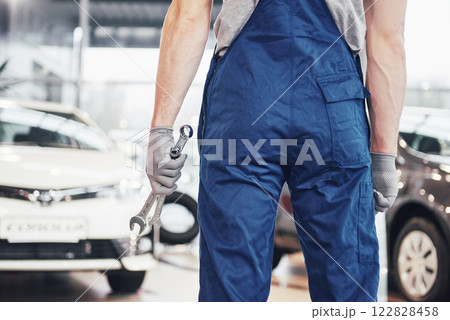 Hands of car mechanic with wrench in garage 122828458