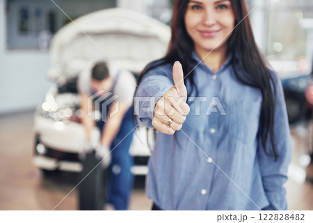 Mechanic holding a tire tire at the repair garage. The woman approves the work done by the client 122828482