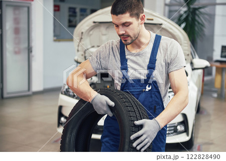 Mechanic holding a tire tire at the repair garage. replacement of winter and summer tires Mechanic holding a tire tire at the repair garage. replacement of winter and summer tires 122828490