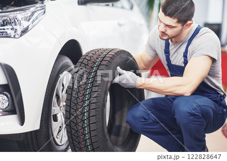 Mechanic holding a tire tire at the repair garage. replacement of winter and summer tires Mechanic holding a tire tire at the repair garage. replacement of winter and summer tires 122828647