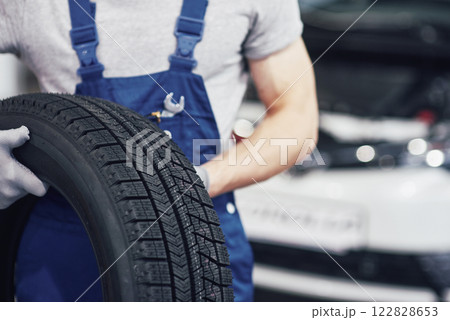 Mechanic holding a tire tire at the repair garage. replacement of winter and summer tires 122828653