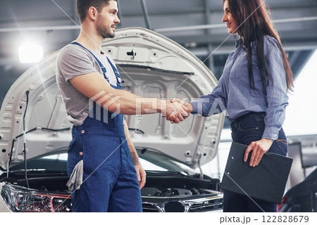 husband car mechanic and woman customer make an agreement on the repair of the car 122828679