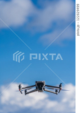 青空を飛行するドローン 122829499