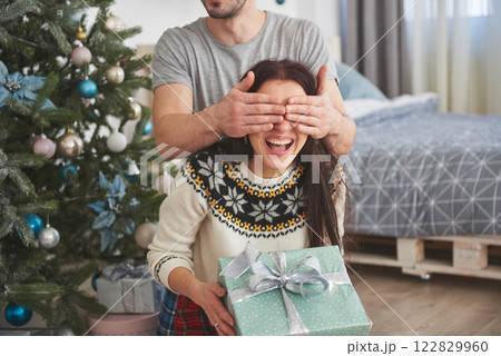 Young couple celebrating Christmas. A man suddenly presented a present to his wife. The concept of family happiness and well-being 122829960