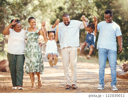 Happy black family bonding and having fun at a park together, laughing and playful holding hands on active walk in nature. African American children enjoy time outdoors with parents and grandparents 122830011