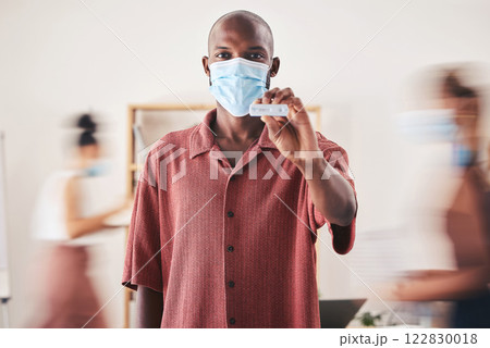 Covid, rapid antigen test and face mask while standing and showing negative medical results. Portrait of a black man looking happy after coronavirus health screening during pandemic at his workplace 122830018
