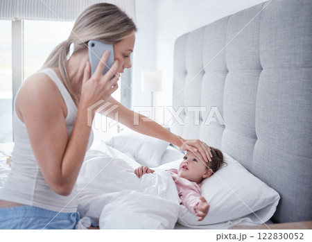 Phone call, sick and child in bed with mother feeling for fever with hand on forehead with worry, care and love. .Family, medical and stress with mom checking health on baby girls head for virus 122830052