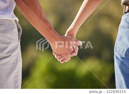 Hand, love and couple with a man and woman holding hands outside in care, trust and relationship. Closeup of a male and female walking outside together for romance and affection with trust outdoors 122830153