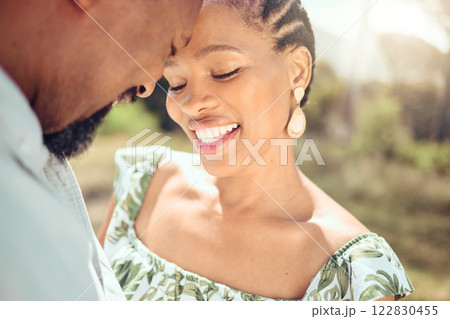 Love, black couple and forehead touch in nature with a smile on holiday or date. Happy black man and woman, romantic African people or lovers bonding in affection together in the shining summer sun. Love, black couple and forehead touch in nature with a smile on holiday or date. Happy black man and woman, romantic African people or lovers bonding in affection together in the shining summer sun. 122830455