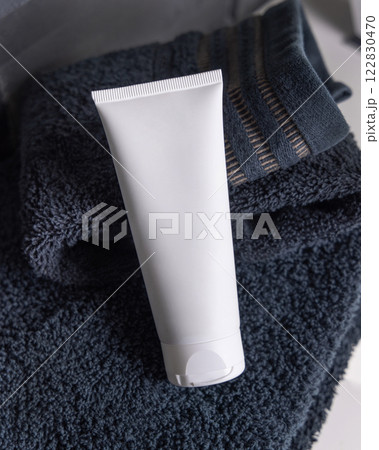White cream tube on black folded towels on basin in dark grey bathroom close up, cosmetic mockup White cream tube on black folded towels on basin in dark grey bathroom close up, cosmetic mockup 122830470