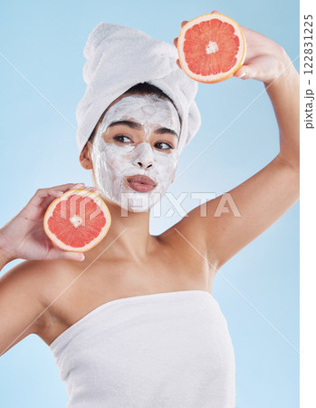 Skincare, health and face mask on a woman with a grapefruit doing an organic facial in studio. Girl with wellness, selfcare and healthy lifestyle doing a body care routine with tropical citrus fruit. 122831225
