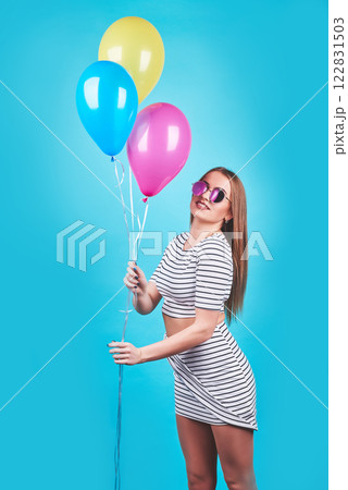 Happy smiling woman is looking on an air colorful balloons having fun over a blue background 122831503