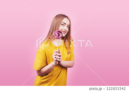 Girl cute funny portrait holding lollipop smiling on pink background. Beautiful multicultural Caucasian girl smiling happy 122831542