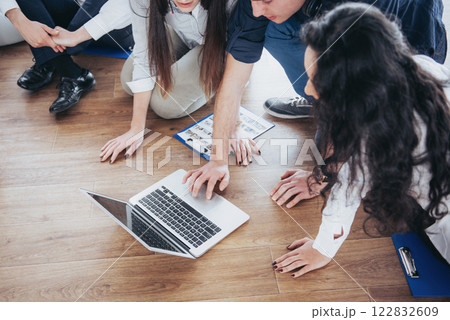 Young creative people in modern office. Group of young business people are working together with laptop. Freelancers sitting on the floor. Cooperation corporate achievement. Teamwork concept 122832609