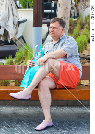 Man in beachwear and karate shoes sitting on bench Man in beachwear and karate shoes sitting on bench 122832789