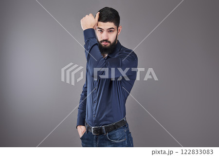 Handsome young bearded man is looking away while standing against gray background Handsome young bearded man is looking away while standing against gray background 122833083