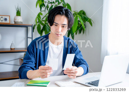 通帳を見つめる男性 122833269