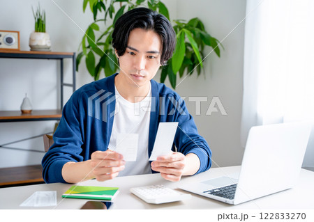 通帳を見つめる男性 122833270