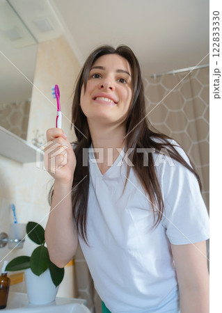 Girl carefully brushes her teeth in the bathroom, taking care of her oral health. She cleans her teeth for a perfect smile. 122833330