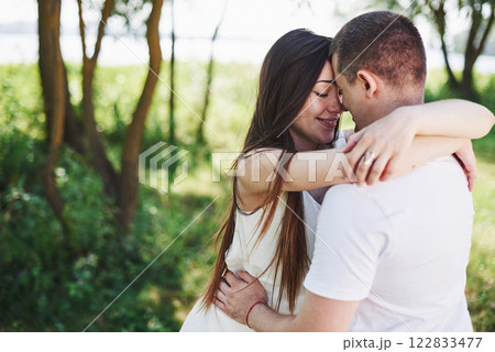 Happy and young pregnant couple hugging in nature Happy and young pregnant couple hugging in nature 122833477