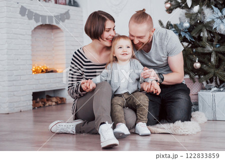 Happy family at christmas in morning opening gifts together near the fir tree. The concept of family happiness and well-being 122833859