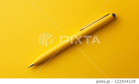 Yellow pen is sitting on a yellow background. The pen is thin and has a silver tip 122834129