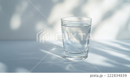 Glass of water is sitting on a table. The glass is half full and the water is clear 122834839