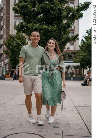 Couple enjoying a casual conversation on a bench outdoors in a city. A couple chats and smiles together while seated on a bench in city Warsaw. Poland. Couple in love visiting Warsaw. 122835242