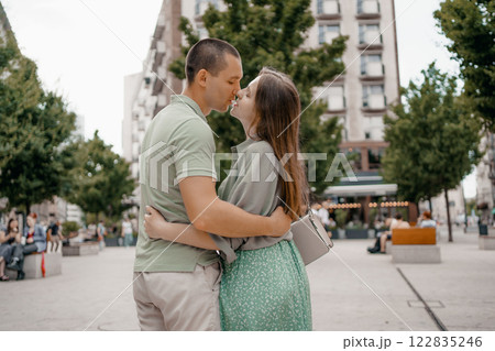 Couple enjoying a casual conversation on a bench outdoors in a city. A couple chats and smiles together while seated on a bench in city Warsaw. Poland. Couple in love visiting Warsaw. 122835246