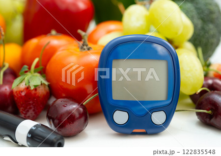 Asian hand holding digital glucose monitor measure with vegetable and fruit healthy food. 122835548