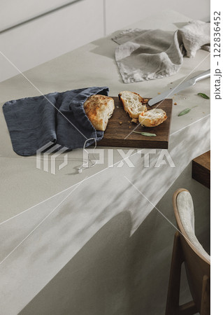 Sliced bread in linen bag on wooden board, fresh herbs and stainless still kitchen knife. Kitchen aesthetic concept 122836452