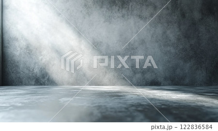 Large, empty room with a wall that is grey and has a lot of texture. The room is illuminated by sunlight coming in through a window 122836584