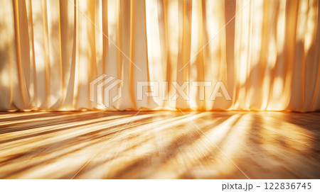 Curtain is hanging in front of a wooden floor. The curtain is white and it is casting a shadow on the floor 122836745