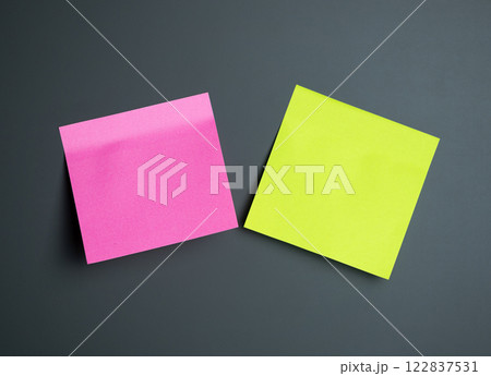 Two colorful sticky notes in pink and green sit on a grey surface Two colorful sticky notes in pink and green sit on a grey surface 122837531