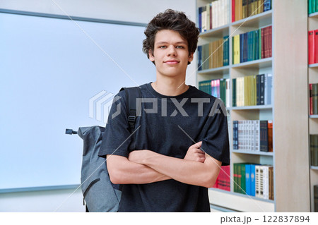 Portrait of college student guy with crossed arms inside library of educational building 122837894