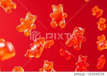 Red gummy bears floating in air on a vibrant red background. Gummy bear candies suspended in mid-air over bright backdrop. Sweets and happy childhood concept. 122838158