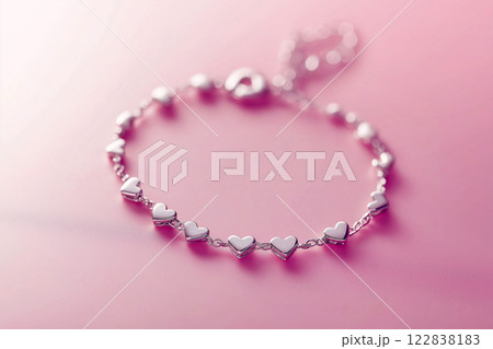 Elegant silver heart bracelet on a soft pink background, romantic design. Delicate heart-shaped bracelet in silver tones, elegance and love symbol on pink. Fashion jewelry, Saint Valentine's Day gift 122838183
