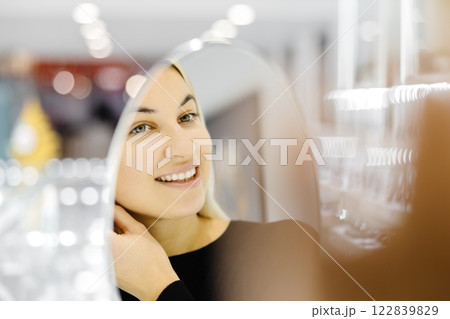 Happy woman trying on gold earrings in jewelry store Happy woman trying on gold earrings in jewelry store 122839829