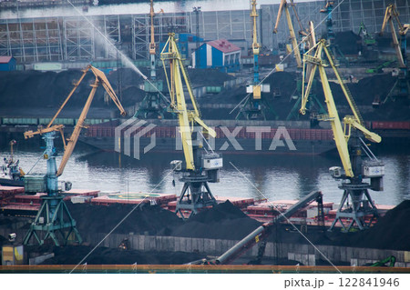 Bustling Industrial Port Cargo Ships moored along Docks, with large Cranes actively loading and unloading coal. Maritime Logistics, heavy machinery, and importexport industry in a waterfront setting Bustling Industrial Port Cargo Ships moored along Docks, with large Cranes actively loading and unloading coal. Maritime Logistics, heavy machinery, and importexport industry in a waterfront setting 122841946