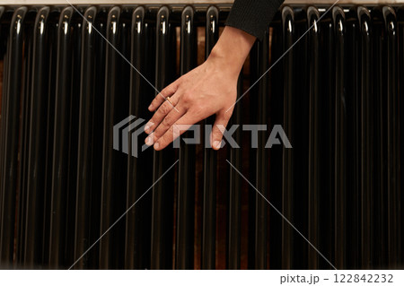 A woman checks the radiator in a cold apartment. Modern radiator for heating in an apartment with power regulators. There is a problem with central heating in the house. High quality photo A woman checks the radiator in a cold apartment. Modern radiator for heating in an apartment with power regulators. There is a problem with central heating in the house. High quality photo 122842232